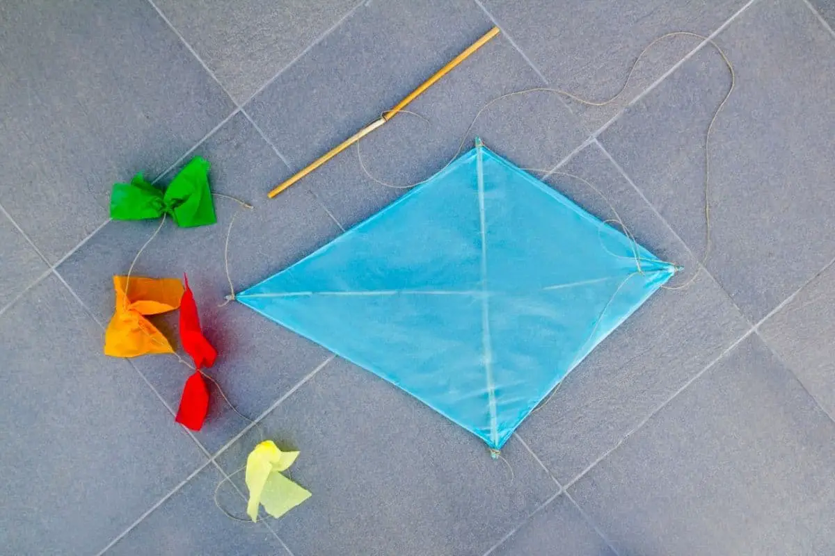 Light-blue paper kite laying on gray tile