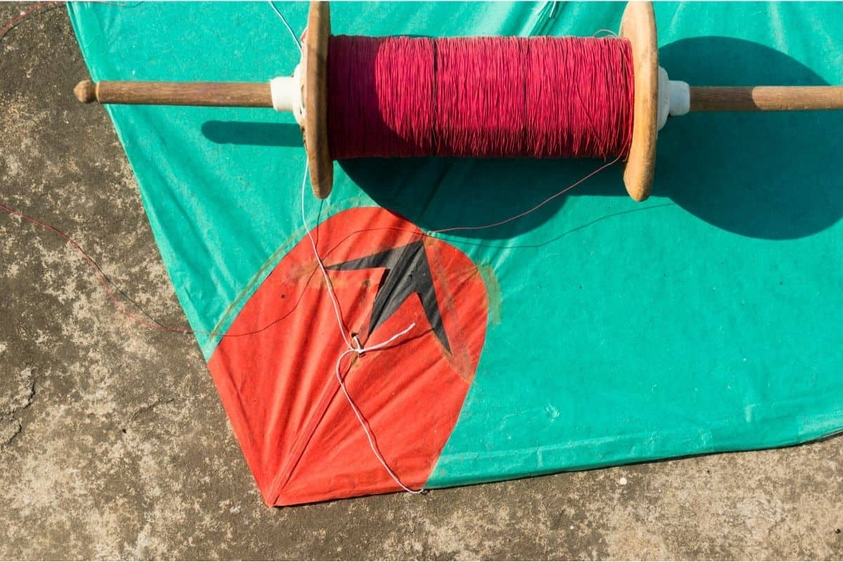 Spool of red kite string laying on a aqua and red kite