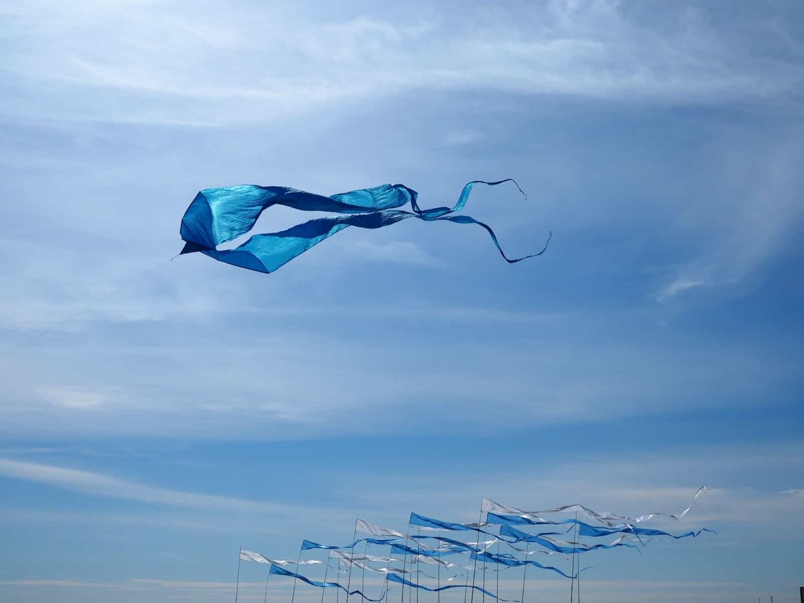 Blue kite in blue sky higher than other blue kites