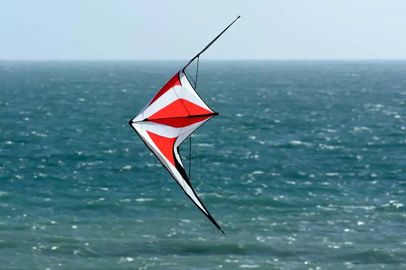Red and white stunt kite over ocean