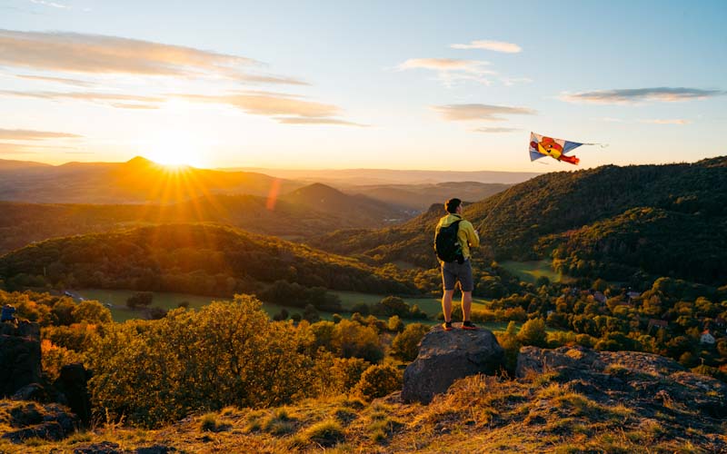 Flying a a kite on a mountain at sunset